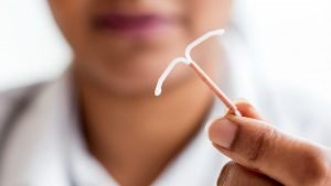 image of a woman holding an iud birth control device in her fingers